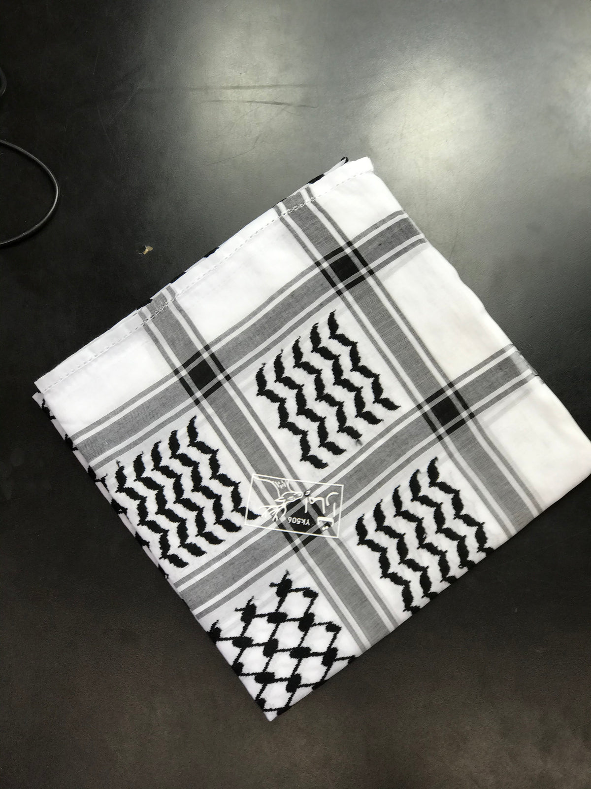 Black and white Palestinian keffiyeh scarf shown folded to display its woven design.