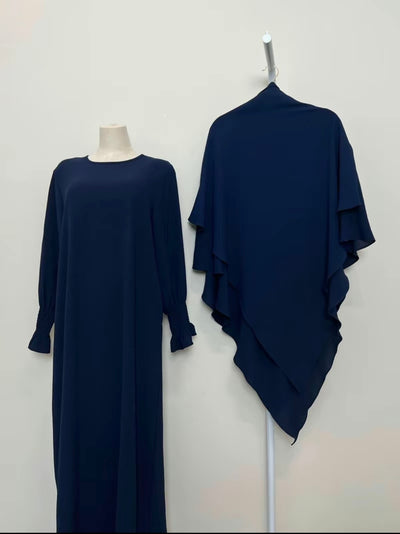 Navy blue dress on a mannequin and draped over a stand against a white background