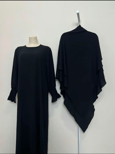 Black dress and black shawl on a mannequin and hanger against a white background
