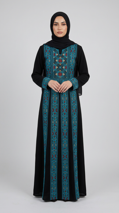 A woman wearing a long black abaya dress with teal and red geometric embroidery down the front panels and sleeves, paired with a black hijab, standing against a light gray studio background.