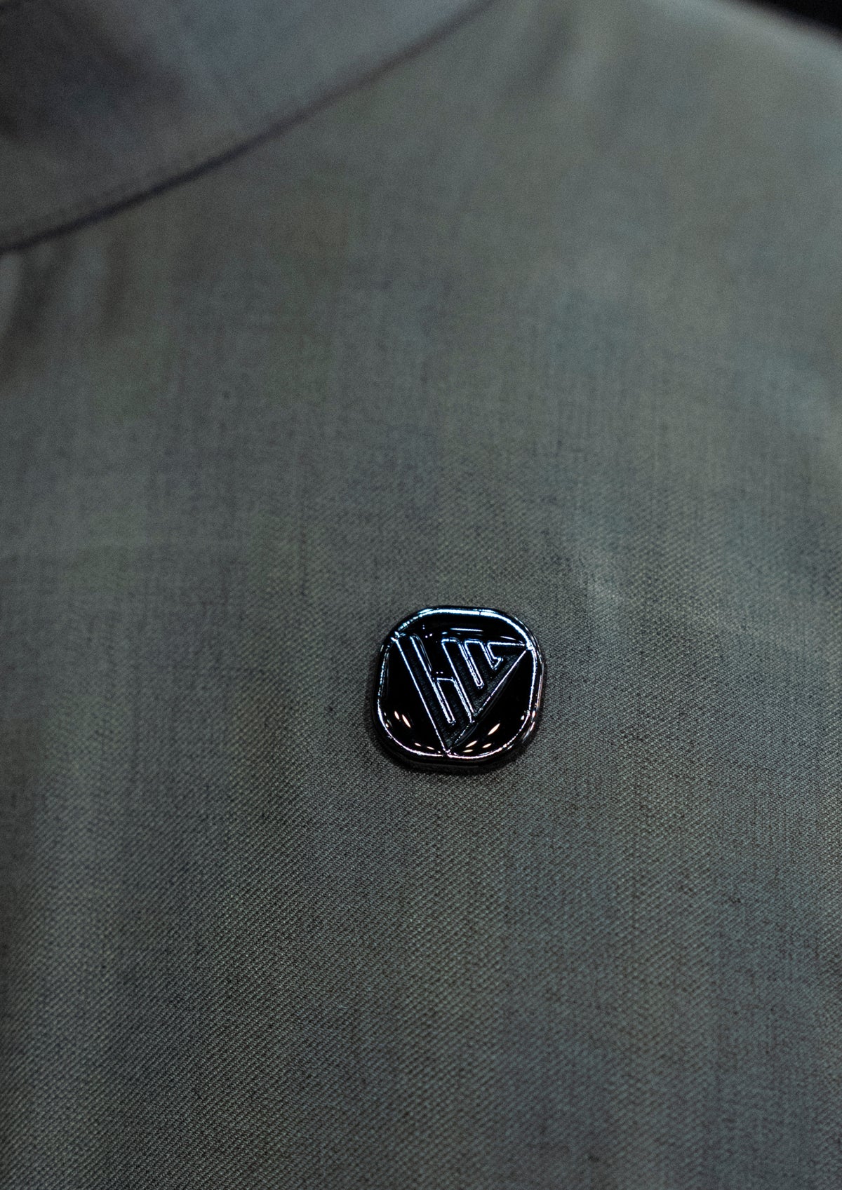 Black logo pin on a gray shirt
