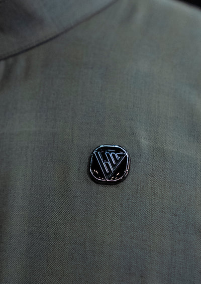 Black logo pin on a gray shirt