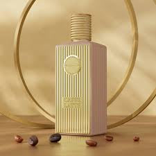A bottle of Khadlaj Caffe Latte perfume with a design that resembles a coffee cup, surrounded by coffee beans and presented against an elegant gold-tone background.