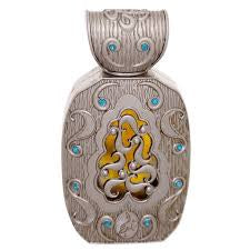 A perfume bottle with a metallic finish and blue gemstone-like accents around the top edge, featuring an intricate design possibly depicting a floral or botanical motif.
