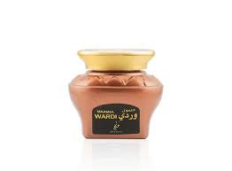 A glass jar with a gold-colored lid containing oud wood chips, labeled as 'WARDI' which is perfumed with roses.